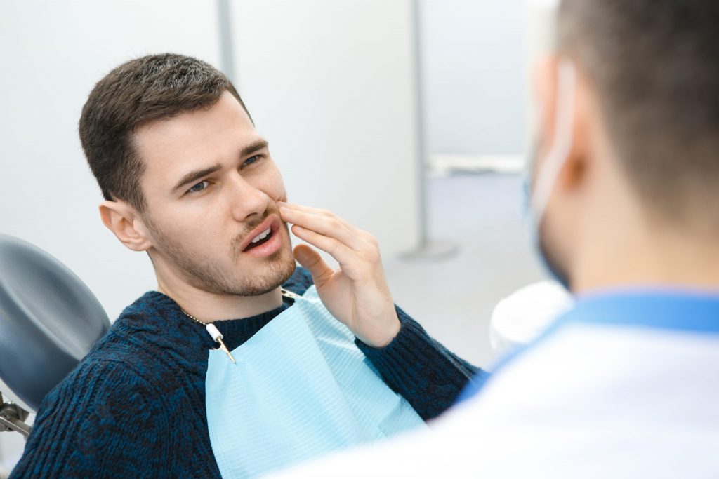 Patient in the dental chair describing where his mouth pain is located.