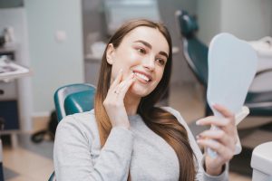 Woman looking at her new smile in a mirror at the dentist's office