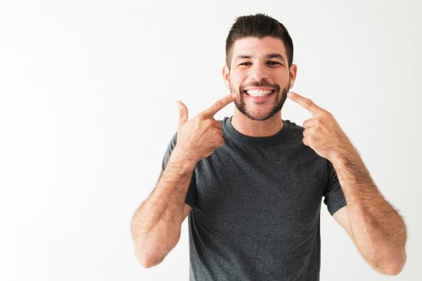 A man points to the results of his teeth cleaning.